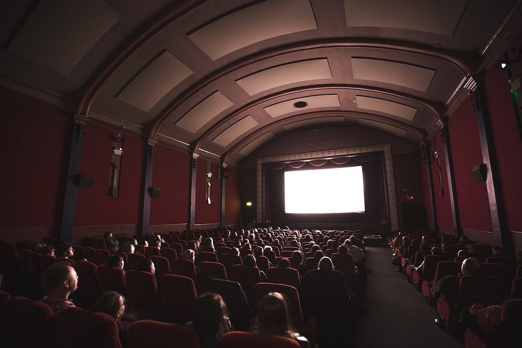 Peoples faces light up in a crowded movie theater — not specifically the Grand Lake Theater in Oakland